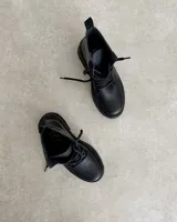 Borcego negro de cuero vacuno con cordones y suela track.