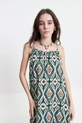 Vestido largo de poliéster con estampado geométrico en tonos borgoña, beige y blanco. Tiene breteles finos y escote redondeado con frunces sutiles en la parte delantera y trasera.