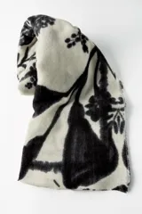 Pañuelo rectangular de color crema con estampado de ramas y flores en negro. Tiene terminaciones deshilachadas.