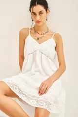 Vestido corto blanco de algodón con puntillas y bordados a tono, corte amplio y breteles regulables.