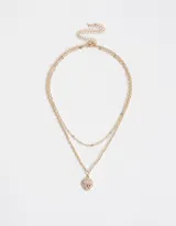 Collar corto dorado con doble cadena, una de eslabones grandes y otra de eslabones pequeños. Dije redondo con diseño de moño rosa y strass.