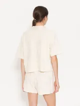 Remera color crema con textura de toalla con diseño floral, cuello camisero y mangas cortas.