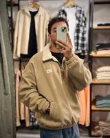 Buzo beige de pana con cuello alto forrado en corderito blanco, cierre parcial con cremallera, puños y cintura elastizados.