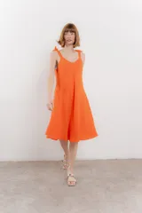 Vestido corto amarillo de lino, con escote en V y tirantes finos con detalle de moño en los hombros.