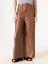 Pantalón marrón de cuero ovino con corte palazzo, bolsillos traseros y cierre frontal con botón.