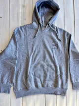 Hoodie gris con capucha y cordón ajustable, corte oversize y estampa en la espalda de una ola dentro de un recuadro.