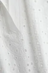 Camisa blanca de algodón con broderie, corte holgado, cuello abierto, mangas anchas al codo y ribete festoneado en mangas y bajo.