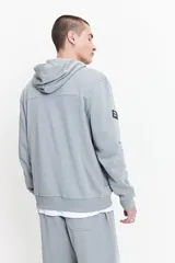 Campera gris de felpa sin frisa, con capucha, cierre frontal y bolsillos laterales con cierre. Logo estampado en relieve en el pecho.