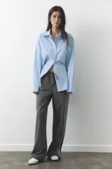 Pantalón de tiro alto negro a rayas verticales blancas, con cintura elástica ajustable con cordones, bolsillos delanteros y banda lateral blanca.