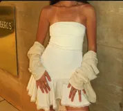 Minivestido blanco strapless ajustado al cuerpo, con falda acampanada con volados y detalle de encaje en el ruedo.