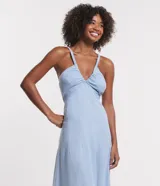 Vestido midi celeste confeccionado en jeans, con tirantes finos, escote en V, lazo en la espalda y detalle cutout.