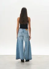 Pantalón de jean celeste de corte mega wide, con cintura alta y ruedo desflecado.