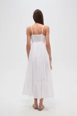 Vestido largo blanco de algodón con broderie, escote en V cruzado y breteles finos. Presenta un corte entallado en la cintura con elástico y falda fluida con tajo lateral.