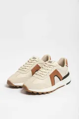 Zapatillas deportivas marrones con detalles en blanco y suela color caramelo.