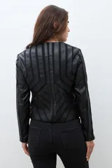 Chaqueta negra de eco cuero con cierre frontal y cuello redondo. Presenta paneles con diseño geométrico de tiras en relieve en el frente y mangas.