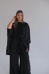 Ruana negra de punto con cuello redondo y diseño asimétrico.