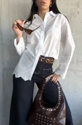 Camisa blanca de algodón con bordado inglés, corte clásico, cuello camisero y mangas largas con puños abotonados.