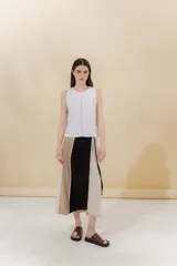 Falda midi de lino y algodón con paneles verticales en color beige, negro y tostado. Diseño portafolio con cruce, abrochada con botones y broches de presión regulables. Detalles desflecados en los cortes verticales y bolsillo escondido en el lateral derecho.