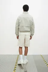 Short cargo color crema en popelina de algodón, con cintura elástica ajustable con cordón, bolsillos laterales y bolsillos con solapa y botones a presión en las piernas y atrás.