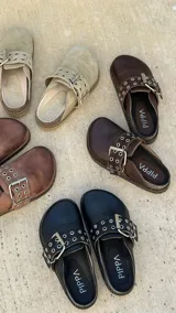 Zueco marrón de cuero con hebilla metálica ajustable, plantilla de cuero y suela de goma.