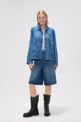 Chaqueta de jean azul con cuello camisero, cierre frontal con lazos y bolsillos de parche.