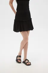 Minifalda negra con cintura alta y volados en el ruedo.
