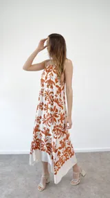 Vestido largo de seda estampada con flores amarillas sobre fondo blanco, corte halter.