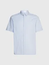 Camisa celeste de popelín de algodón superelástico, con cuello en punta, manga corta, tapeta con botones y logo con monograma de Calvin Klein en el pecho.