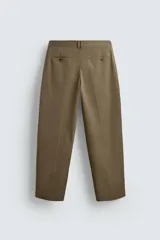 Pantalón color caqui de corte tapered relaxed fit, confeccionado en tejido de algodón. Presenta cintura con pliegues frontales dobles, bolsillos laterales en cadera y bolsillos traseros de vivo con botón. Cierre frontal con cremallera y botón.