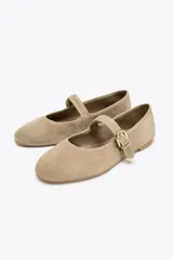 Bailarinas color beige de gamuza con tira sobre el empeine y hebilla dorada.