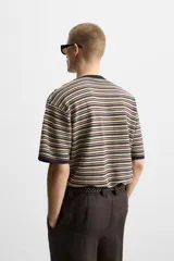 Camiseta de hombre de punto a rayas horizontales en tonos verde, rojo y negro. Corte regular fit, cuello redondo y manga corta con terminaciones en rib.