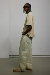 Pantalón de jean color crema, de corte holgado, con tiro bajo y cinco bolsillos.