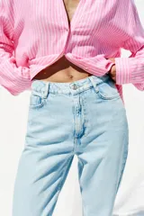 Pantalón de jean celeste claro, de corte mom fit, tiro alto y largo tobillero.