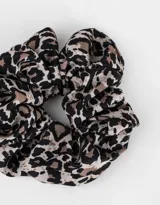 Scrunchie de tela con estampado animal print en tonos negro, marrón y beige.