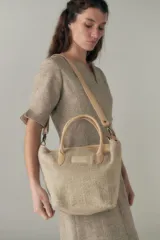 Cartera tipo tote de lana color beige con forro, cierre y asa de cuero regulable.