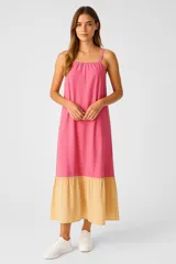Vestido largo de lino color rosa y amarillo, con breteles finos, corte holgado, bolsillos laterales y falda con volantes.
