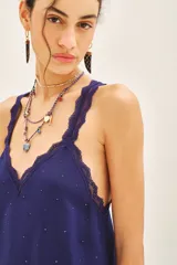 Top bretelero azul oscuro con escote en V, ribetes de puntilla a tono en escote, breteles y sisas. Presenta tachas termo adhesivas distribuidas en el frente.