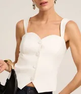 Blusa blanca de tejido plano en sastrería, con escote corazón, breteles anchos, botones forrados, elástico en la espalda y bajo con recorte V.