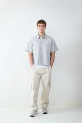 Pantalón cargo beige de corte recto confeccionado en 100% algodón, con múltiples bolsillos delanteros, laterales y traseros.