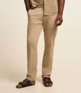 Pantalón de vestir color marrón, de corte recto, con bolsillos laterales y traseros. Se ajusta a la cintura con cinturón de cuero marrón.