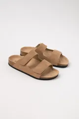 Sandalias planas color beige con dos tiras con velcro ajustables sobre el empeine y plantilla de corcho.