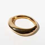 Brazalete rígido dorado con forma ovalada.