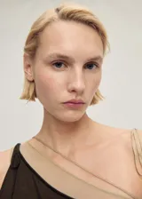 Vestido midi asimétrico de punto fino color marrón, con un tirante fino y corte entallado. Incluye un cinturón de cadena plateada con dije.