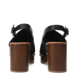 Sandalia de mujer con capellada de cuero negro, diseño cerrado en la punta (peep-toe) y pulsera ajustable con hebilla dorada en el tobillo. Posee una plataforma y taco alto de madera oscura, con detalles de tachas metálicas doradas en la unión entre la capellada y la plataforma.