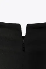 Vestido midi negro sin mangas, con cuello alto y detalle drapeado en el delantero. Cierre con cremallera oculta en la espalda.