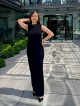 Vestido largo negro, ajustado al cuerpo, con cuello redondo y sin mangas.