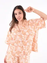 Camisa salmón con estampado de flores blancas, de corte holgado, cuello clásico y mangas cortas.