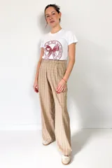 Pantalón de vestir de corte sastrero con estampado escocés en tonos beige y marrón. Tiene pinzas delanteras, bolsillos laterales y un bolsillo trasero con bordado.