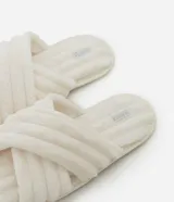 Pantuflas tipo ojota de color blanco hueso, con textura peluda y tiras cruzadas en la parte superior.