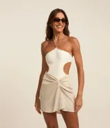 Salida de playa tipo pollera corta, color beige, confeccionada en lino y viscosa. Presenta cintura elástica y nudo decorativo en el frente.